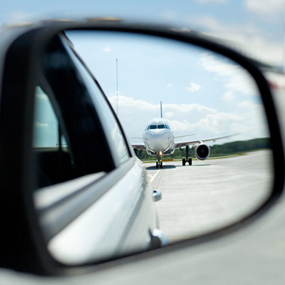 Commercial airplane reflected in car side mirror